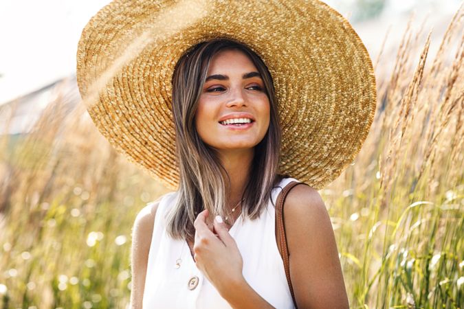 Smiling woman in sunhat enjoying a sunny day in the field
