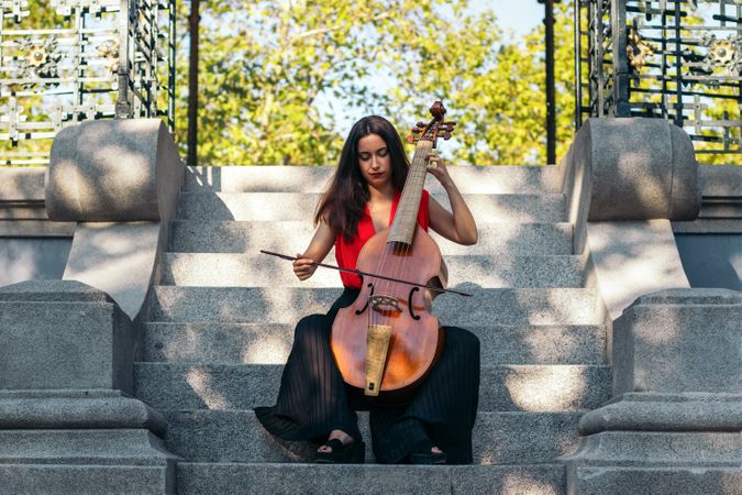 A young woman playing the cello outdoors