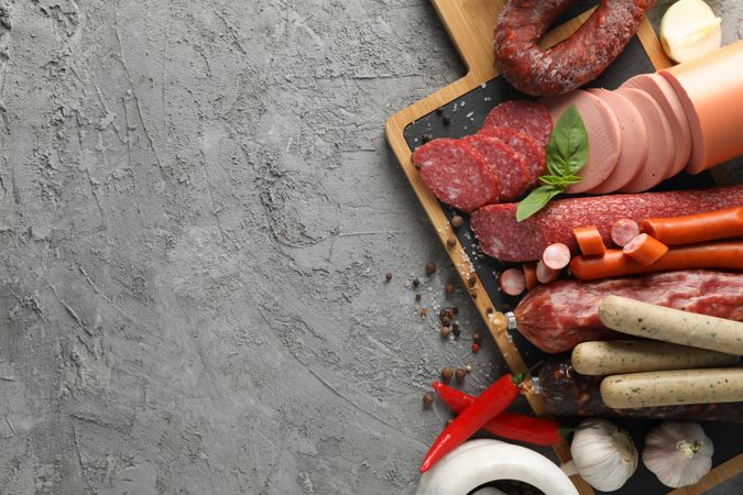 Top view of kitchen board with cured meats and mortar, copy space