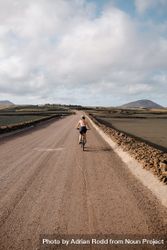 Back of female biking on Lanzarote dirt road, vertical 5lLGV5