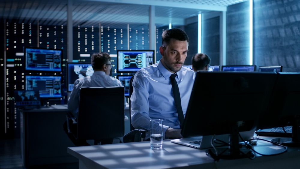 Close-up of Technical Engineer Working on His Computer With Multiple Displays in Monitoring Room.