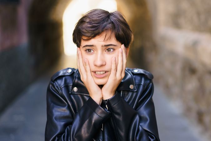 A Young Individual Wearing a Leather Jacket Conveying Strong Emotions in an Alleyway