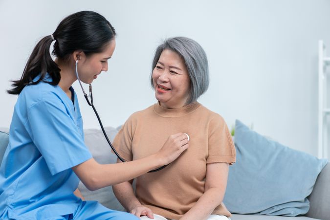 Nurse listening to heart beat of female patient