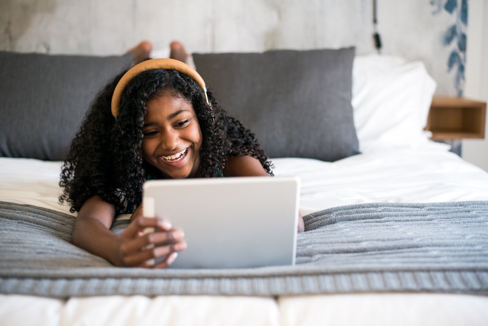 Black girl using tablet in bed