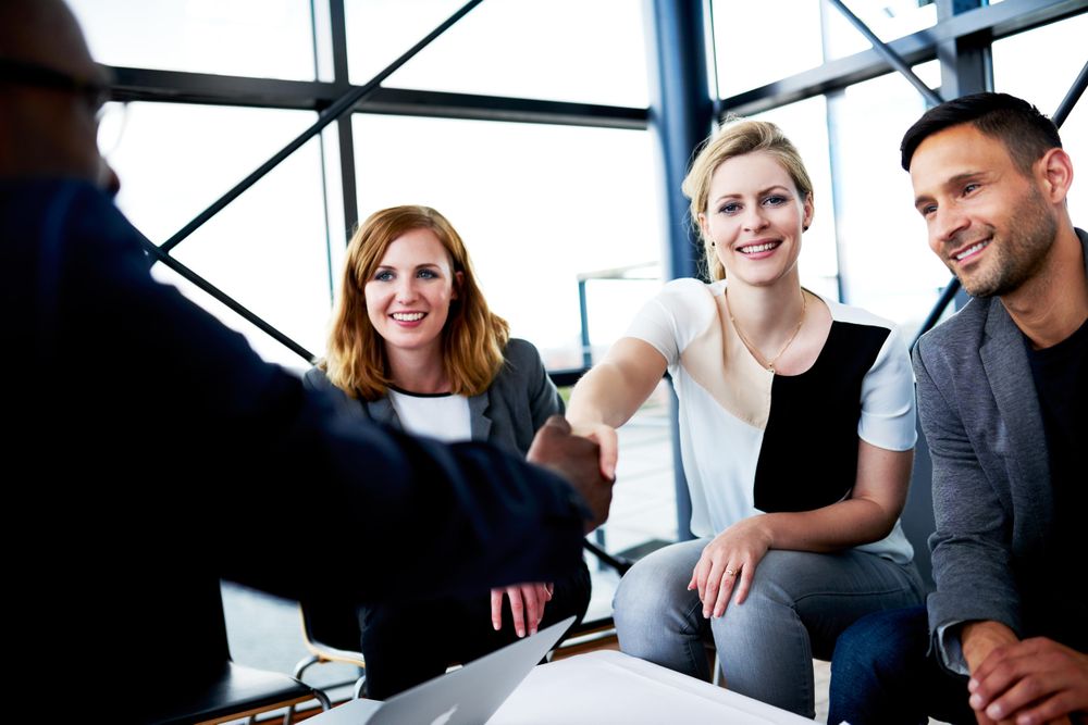Smiling female business associates shaking hands at an informal meeting in an office