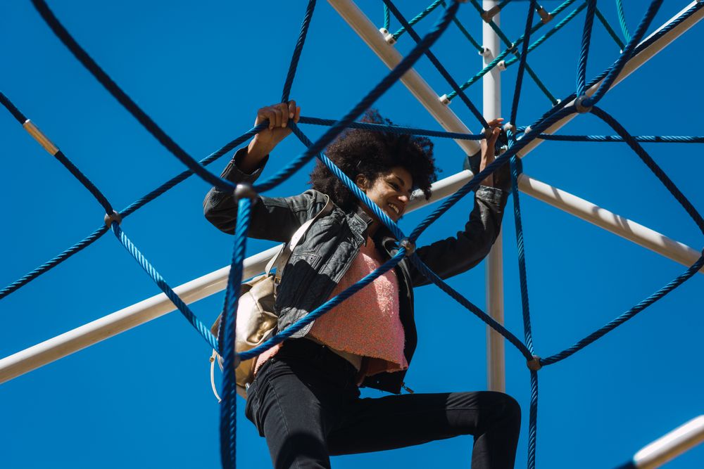 Woman with afro hair climbing by children's attractions.