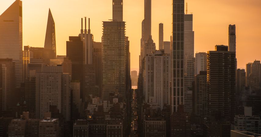 Beautiful Cinematic Aerial Sunset Shot of New York City Skyscrapers and Busy City Streets with Car Traffic. Panoramic Helicopter View of Lower Manhattan Office Buildings