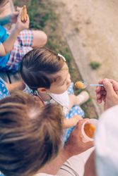 Top view of man feeding baby girl sitting in a bench