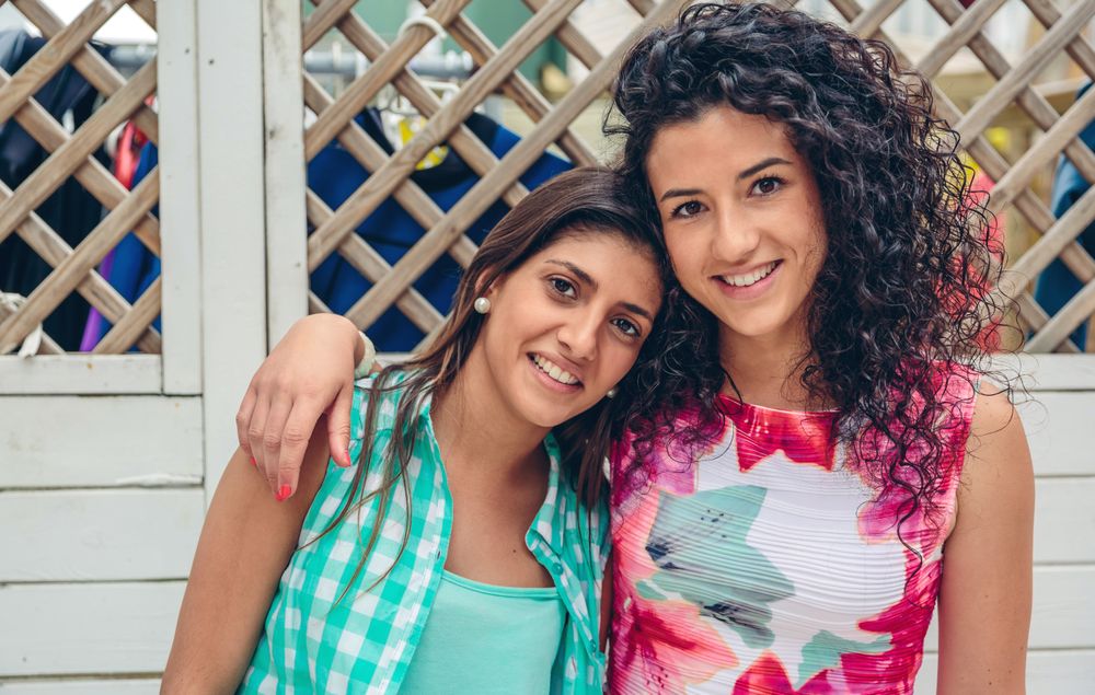 Two female friends with arms around each other's shoulder