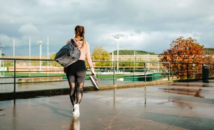 Sportswoman with gym bag and sports shoes walking to go to training