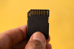 SD card in hand with yellow background and space for text