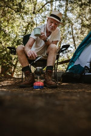 Older man making coffee outdoors on a camping trip