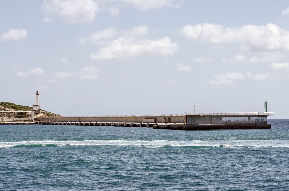 Lighthouse tower near a concrete pier walkway