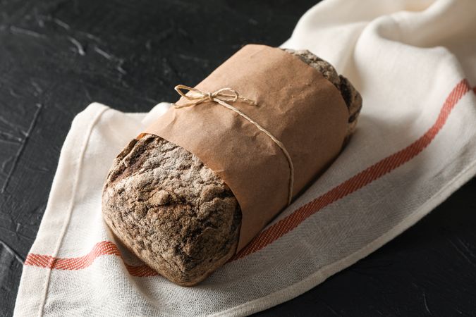 Rye bread on kitchen towel on table against wooden background, space for text and closeup
