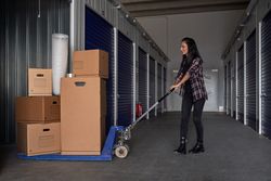Content woman using pallet truck with packing boxes