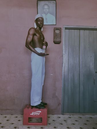 Topless man holding a bottle standing on step stool