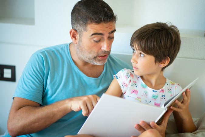 Dad with child reading in bed