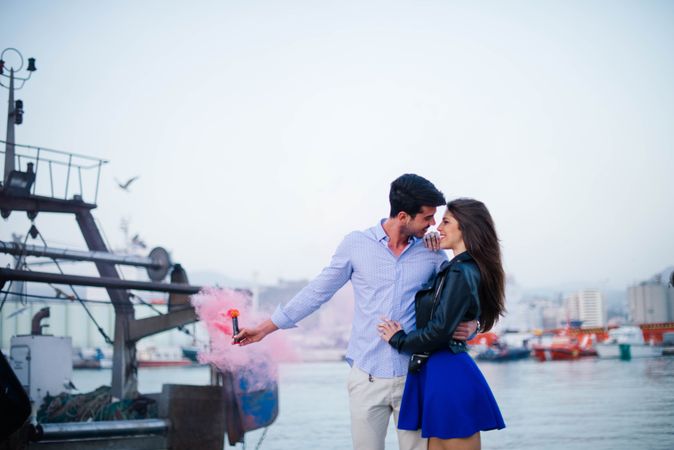 Young man holding smoke bomb and hugging woman being in love
