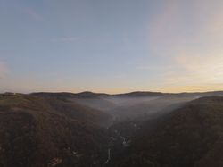 Sunrise Over Forested Hills and Winding Road in Misty Valley.