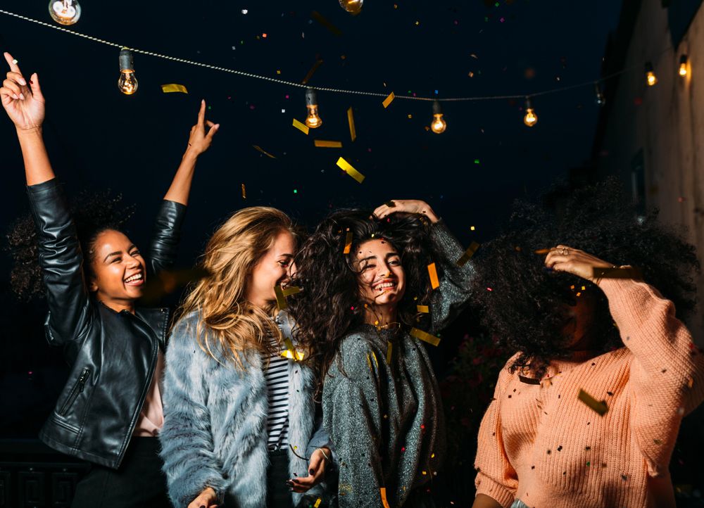 Group of female friends throwing confetti and celebrating at night