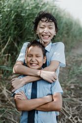 Happy kid hugging younger brother in nature