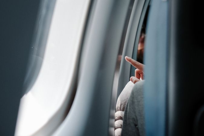 Anonymous hand pointing out an airplane window