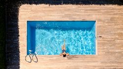 Anonymous woman sunbathing in outdoor swimming pool