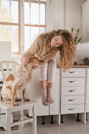 Young woman with dog in cozy kitchen