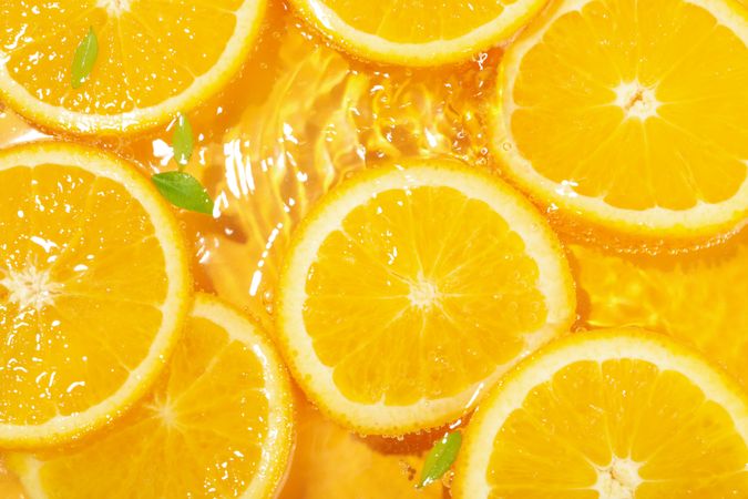 Top view of orange slices with leaves in fresh water