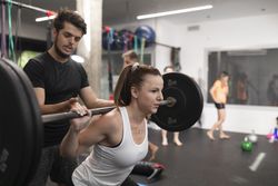 A female trainee squats at the gym