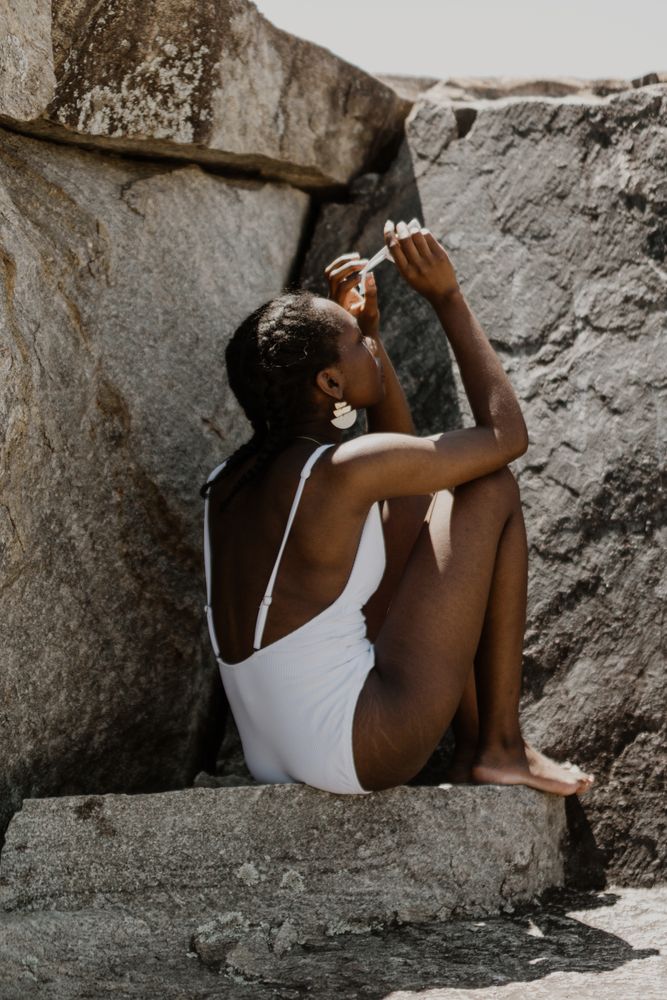 Back view of woman swimsuit sitting on a rock