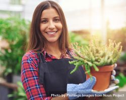 Woman holding terra-cotta planter in a greenhouse 0Knqzb