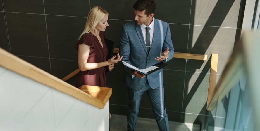 Businessman talking with female colleague in office stairway