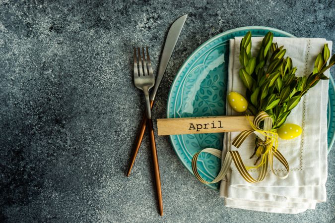 Easter card concept of branch and yellow mini eggs on table setting with copy space