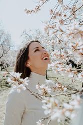 Young happy woman between trees in garden