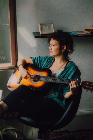 Content woman playing guitar at home