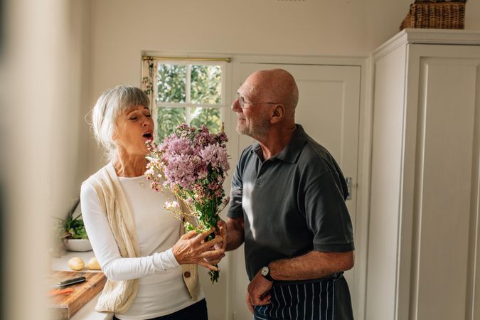 Man expressing his love for his wife giving her a bunch of flowers at home