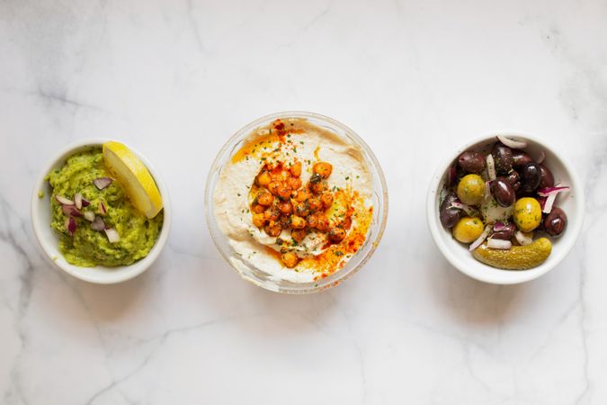 Appetizing hummus and sauces decorated with green on table