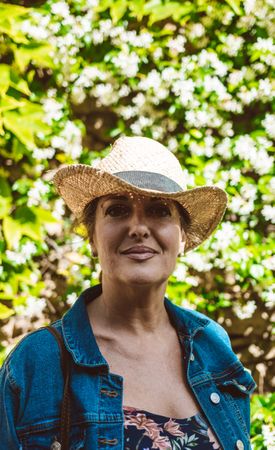 Woman standing near a wall with flower shrubs