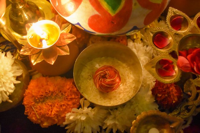 Top view of Mauli thread ball in rice bowl surrounded by diyas