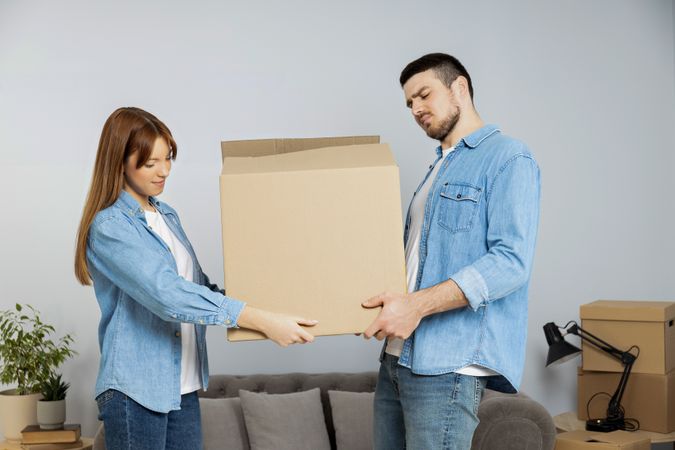 Moving concept, couple man and woman with boxes in apartment.