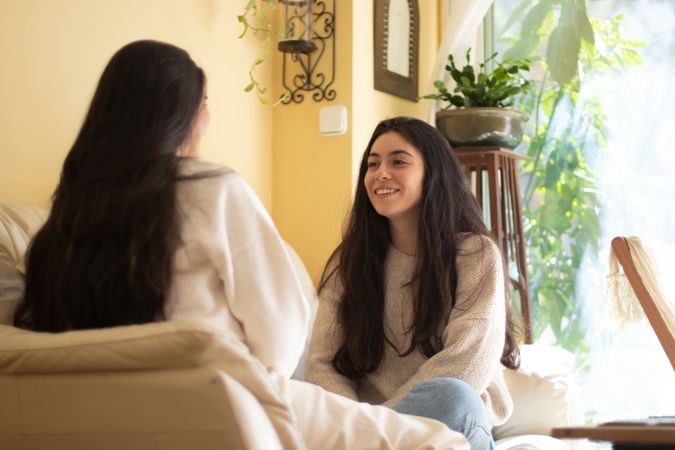 Smiling Young woman talking with her mother sitting on a sofa at home.