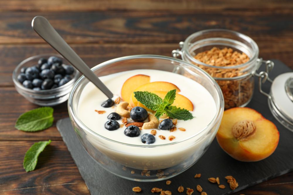 Composition with yogurt dessert and ingredients on wooden background, space for text