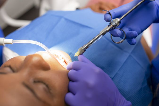 Hands of dentist injecting patient's mouth with syringe