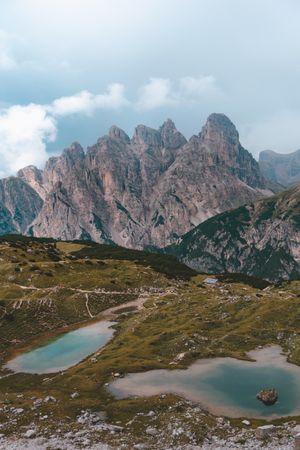 Two lakes on hills against Dolomites mountains during fair weather