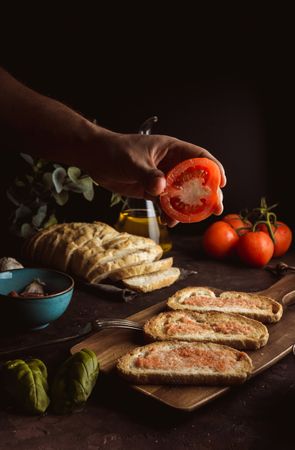 Crop person pouring tomato on toasts