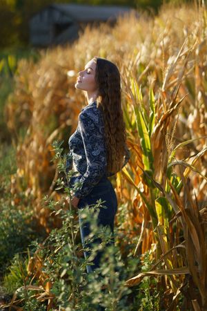 A Serene Young Woman Enjoying the Beauty of a Cornfield During a Vibrant Sunset Scene