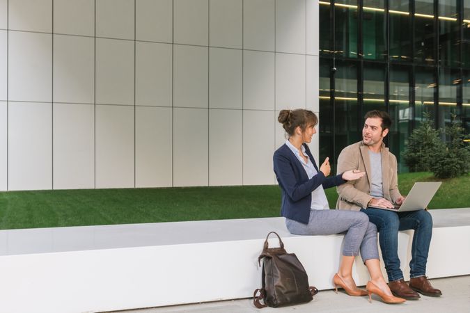 Cheerful colleagues using laptop on street