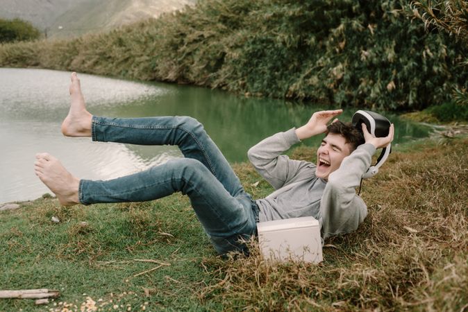 Young teenager with virtual reality glasses laughing outdoors