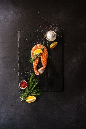 Salmon fish with rosemary and lemon on dark counter with copy space